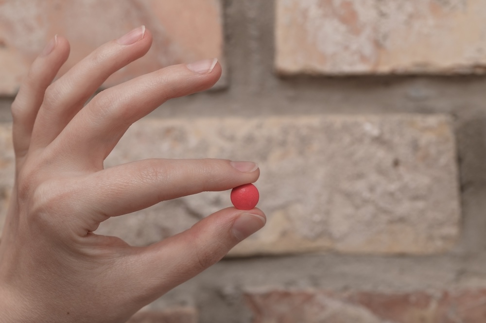 Man holding a triple c red pill wondering if addiction is deadly